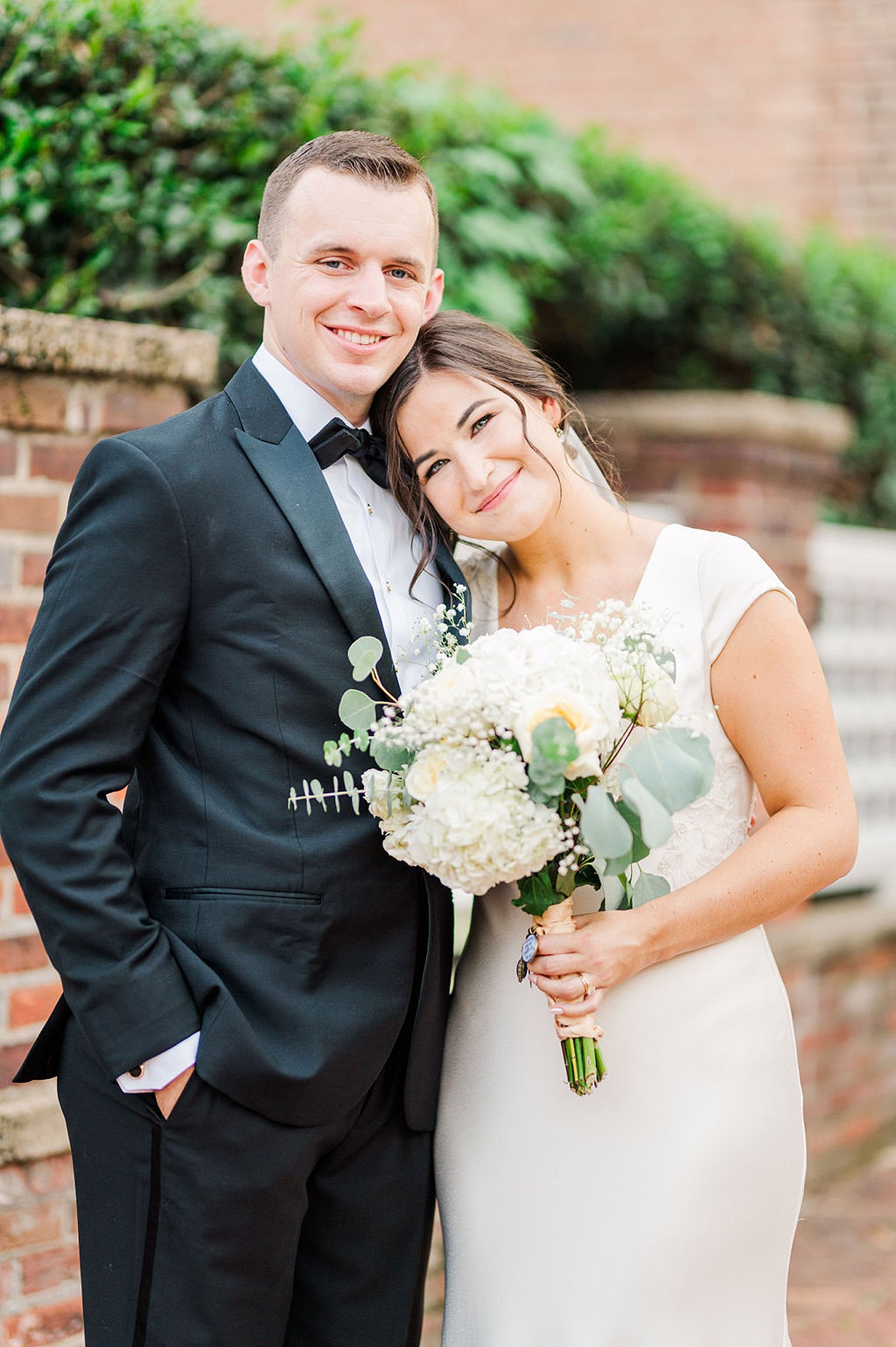 bride leaning on her groom while holding her bouquet at their old town alexandria wedding