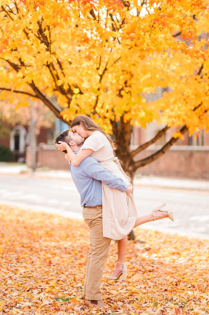 man lifting his fiance in the air and sharing a kiss during the fall Engagement Photos Richmond VA