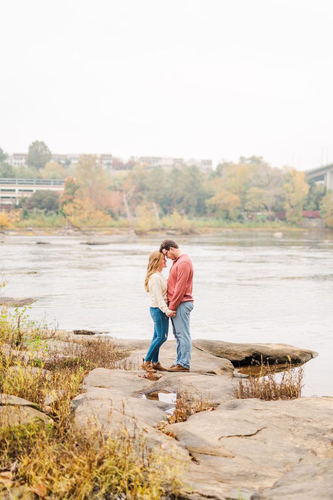 couple holding hands with their heads together on a rock at brown's island
