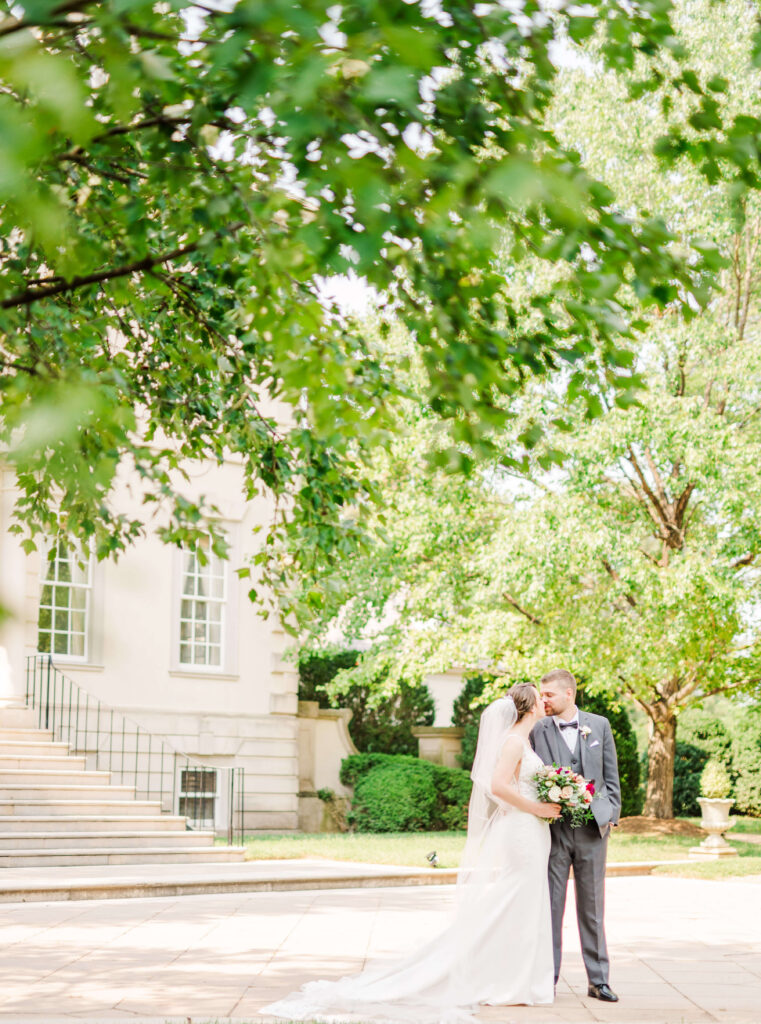 wedding couple kissing in front of Great Marsh Estate