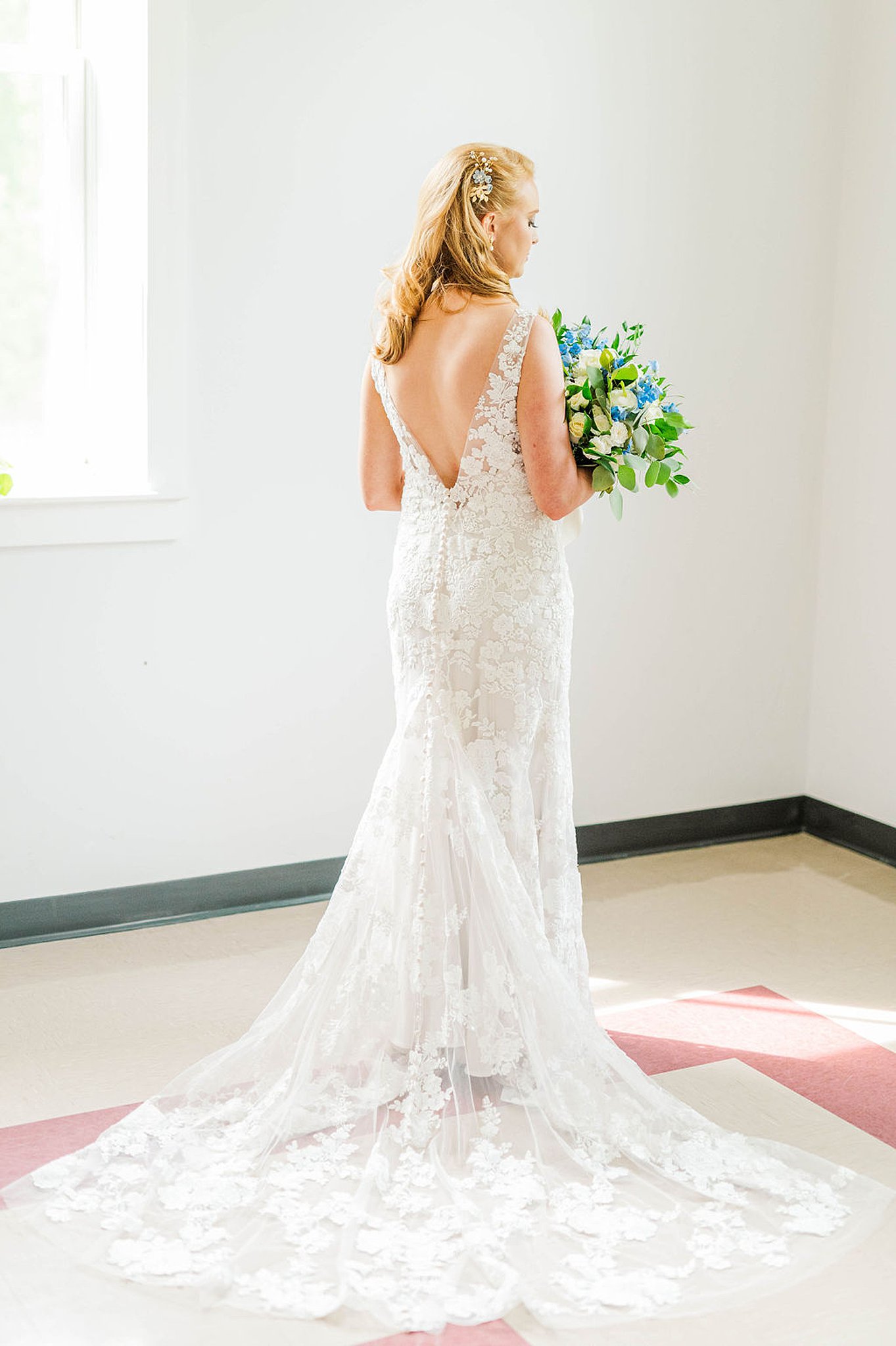 bride stands in the corner of a room holding her bouquet