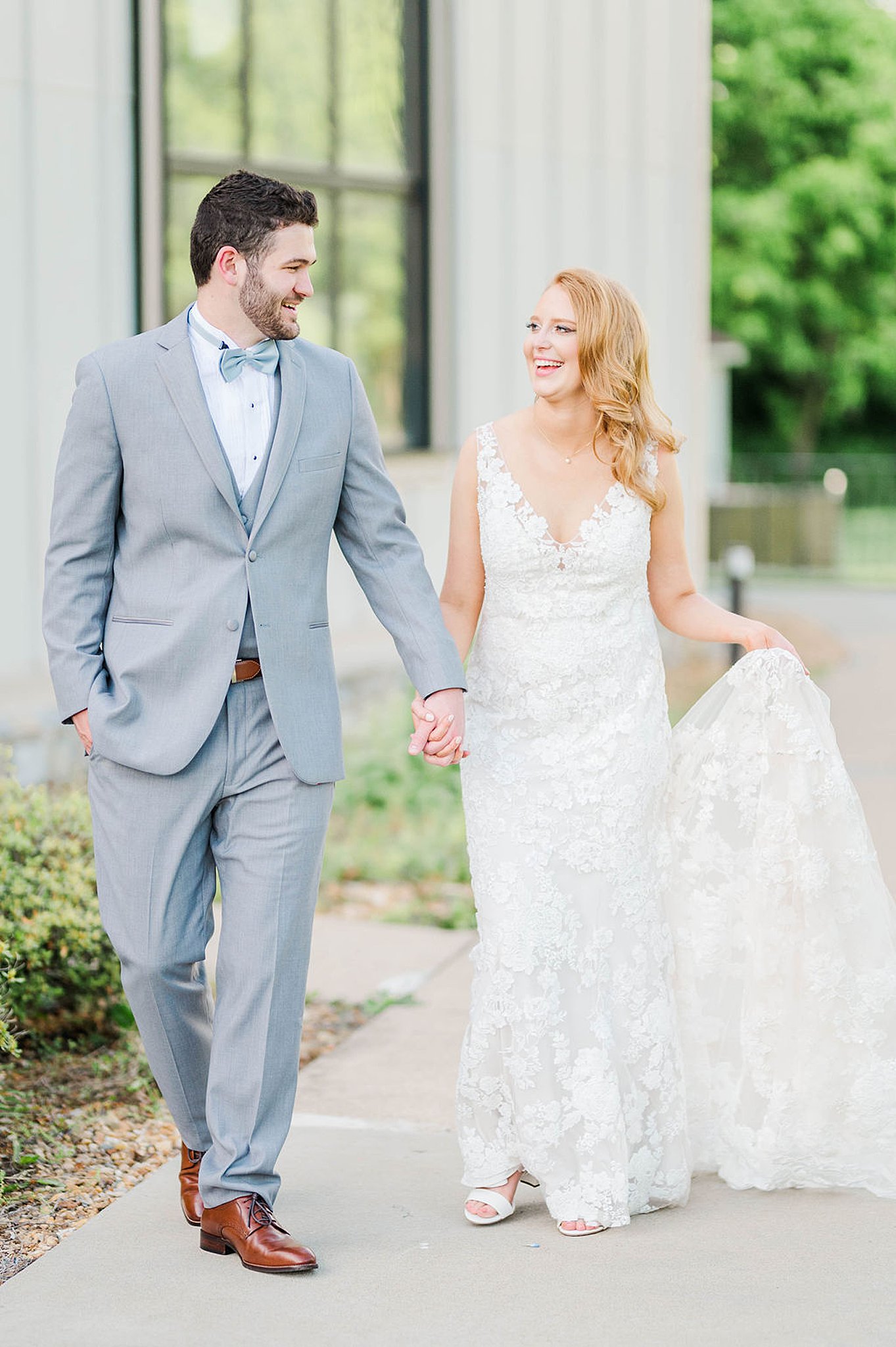 bride and groom walk down sidewalk holding hands