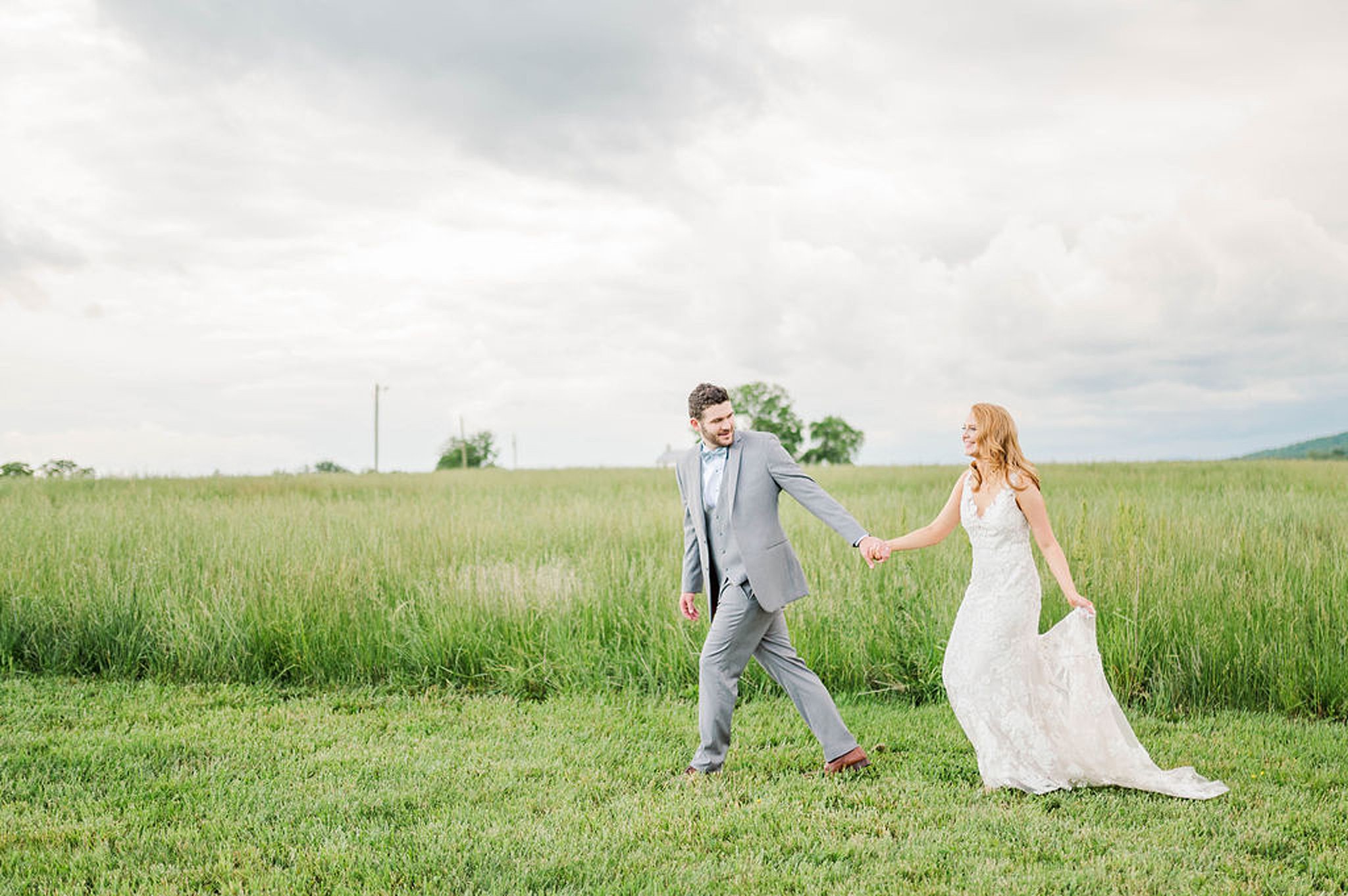 bride and groom in grey suit walk through a grassy field Richmond Weddings