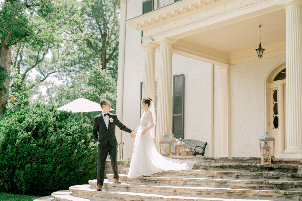 groom escorts bride down steps at wedding mansion in Leesburg VA