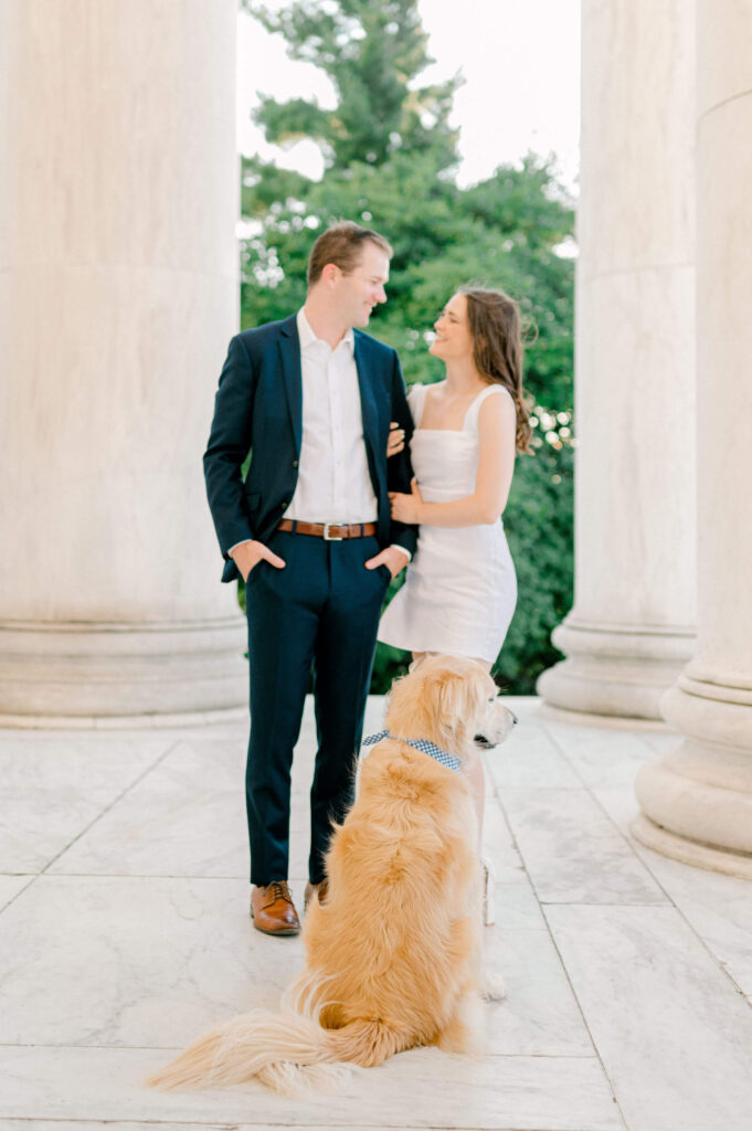 Couple looking at each other with dog during engagement photos