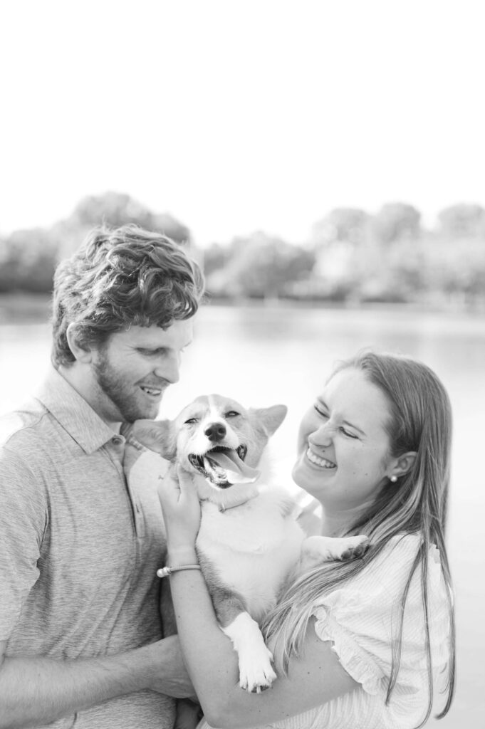 black and white photo of couple laughing with dog
