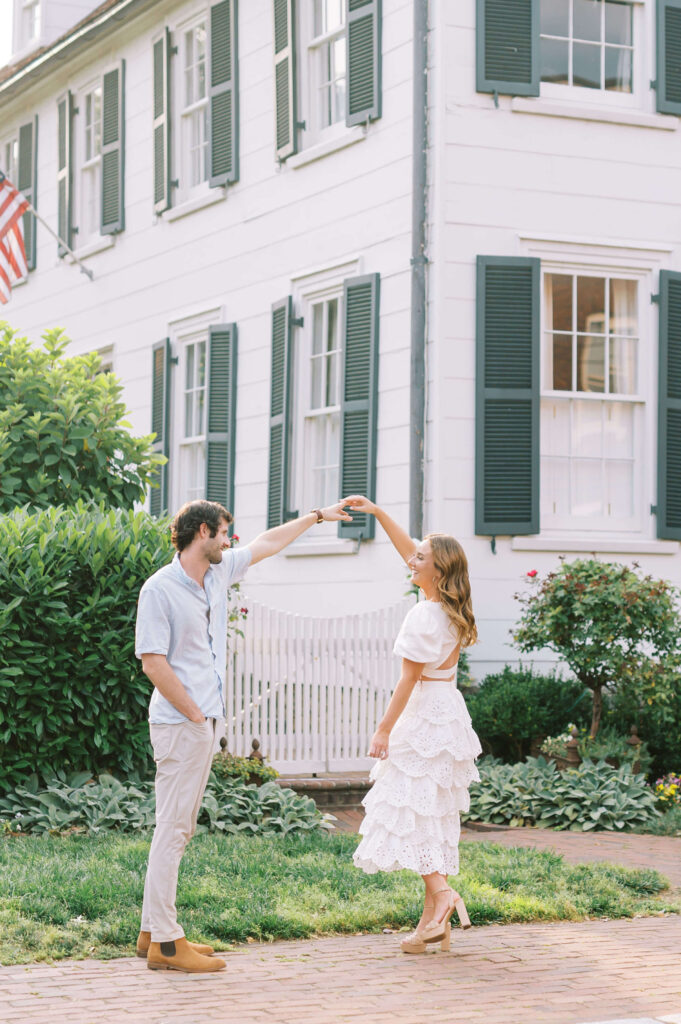 Woman in white scalloped dress dancing with her fiance during engagement photos