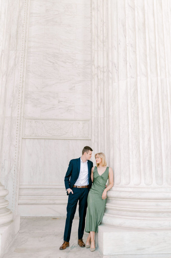 Couple leaning onto the U.S Supreme court columns during engagement session. 