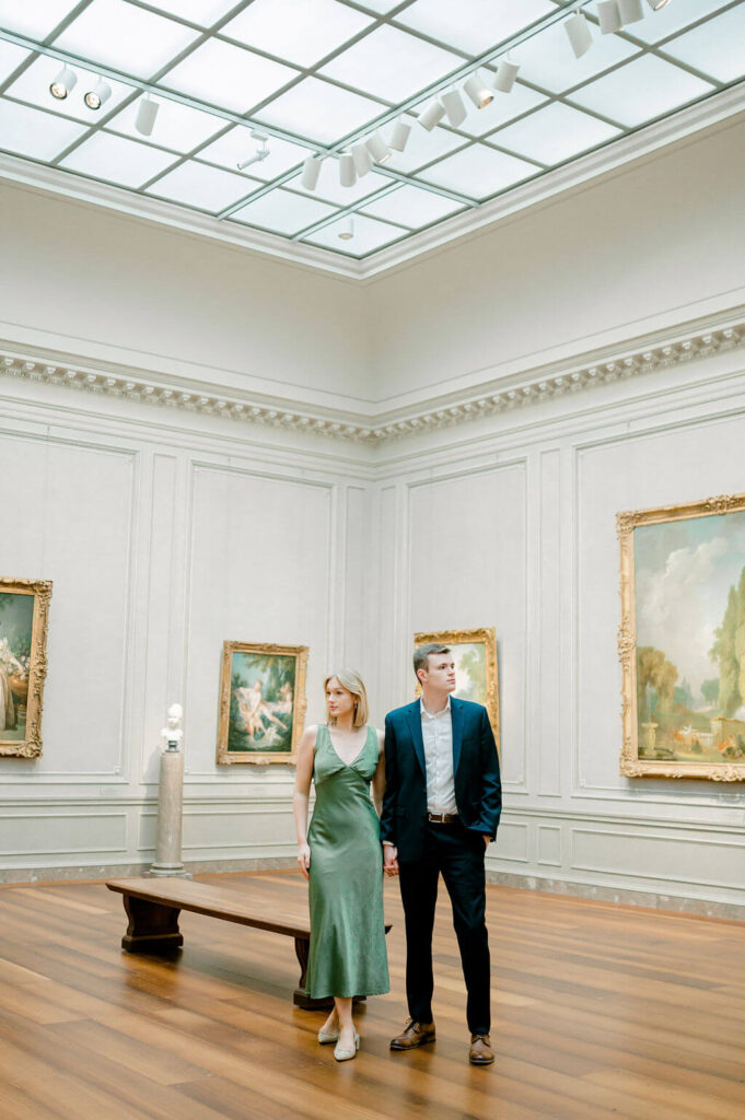 Couple holding hands in an art gallery during their engagement session. 
