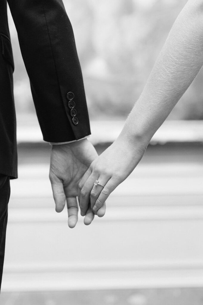 A black and white image of a couple lightly touching hands during their engagement session. 