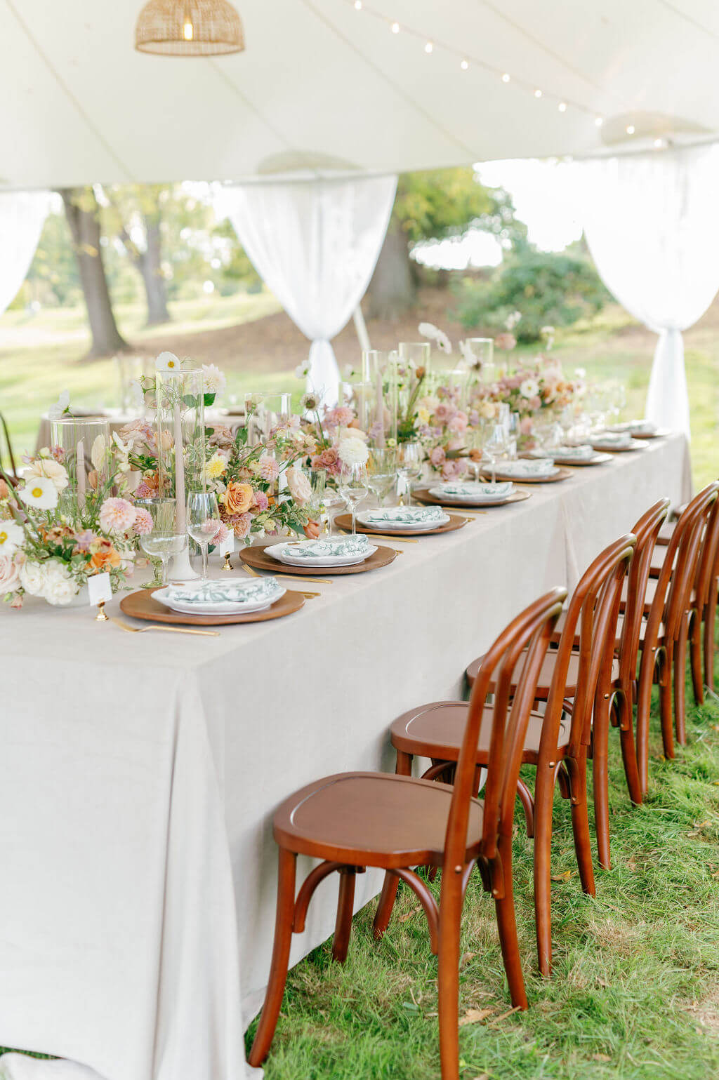 Elegant outdoor reception table under a white tent at The Willows at Ashcombe Mansion, decorated with blush and peach florals.