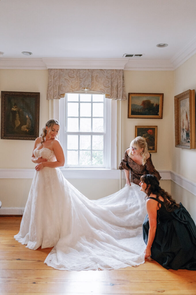 Bride with mother and sister as they fluff out her wedding dress