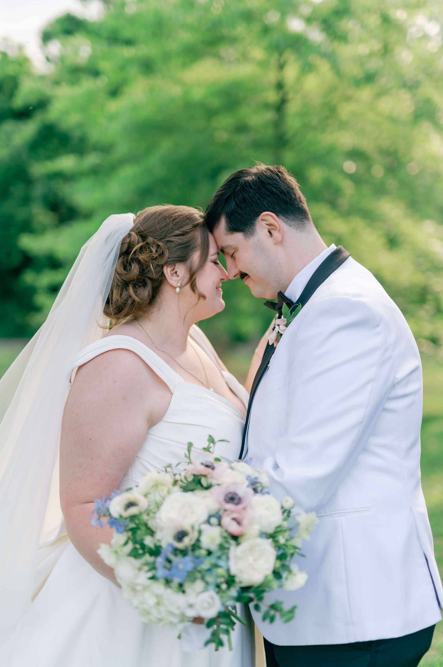 A happy newlywed couple touch foreheads in a forest at sunset during their clifton inn wedding
