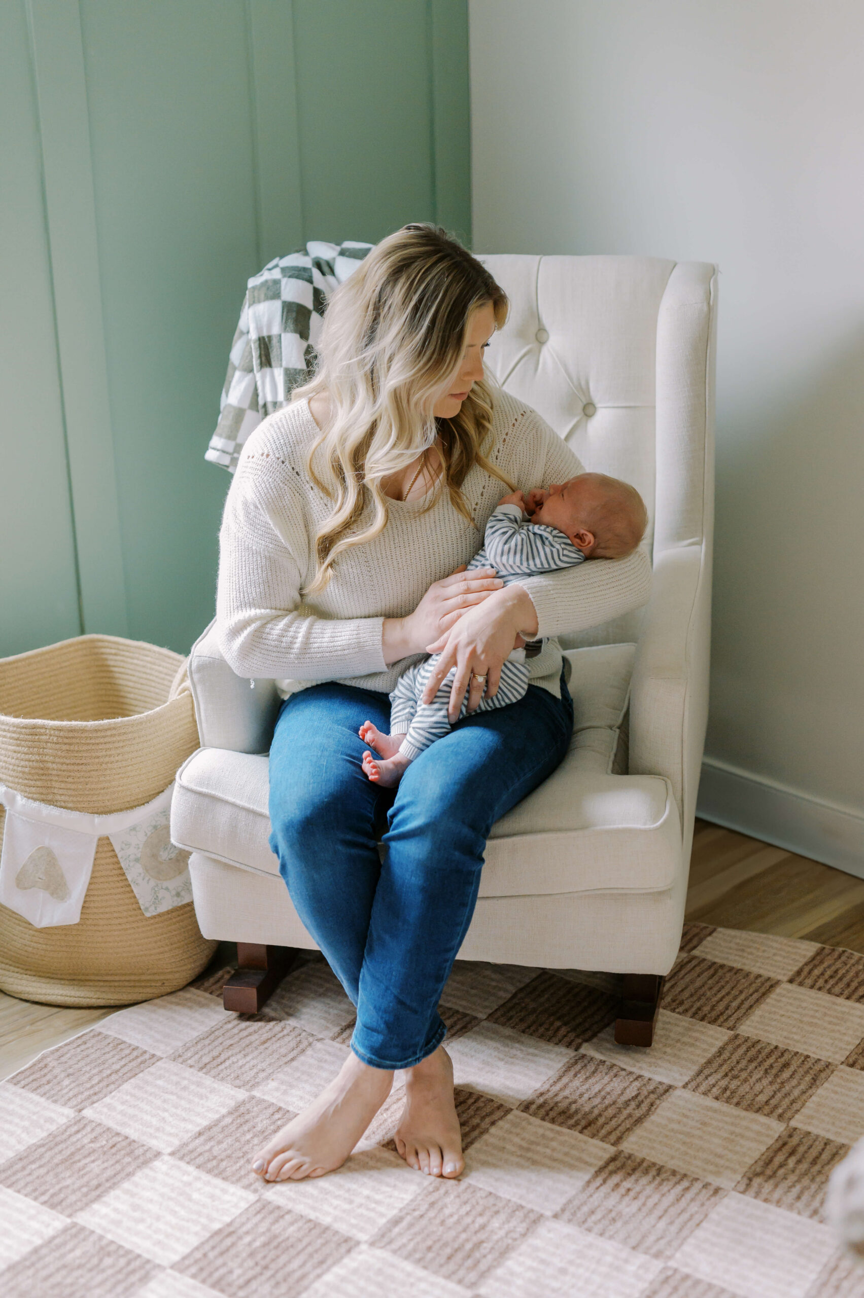 A newborn lays in mom's arms while sitting in a nursing chair after meeting nannies in Richmond, VA