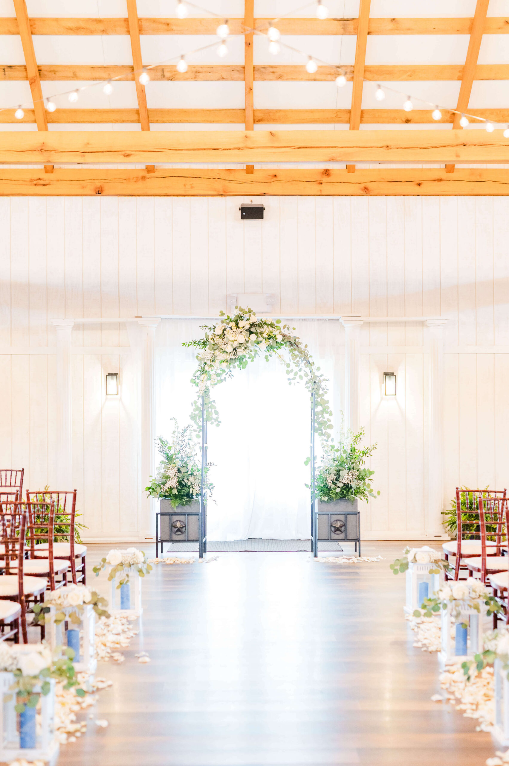 Details of a wedding ceremony arbor set up indoors covered in white roses