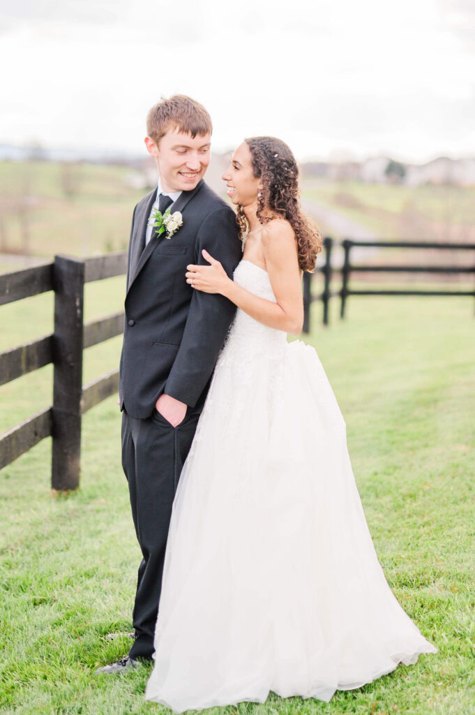 Newlyweds smile at each other while admiring the view in a pasture at their shadow creek wedding