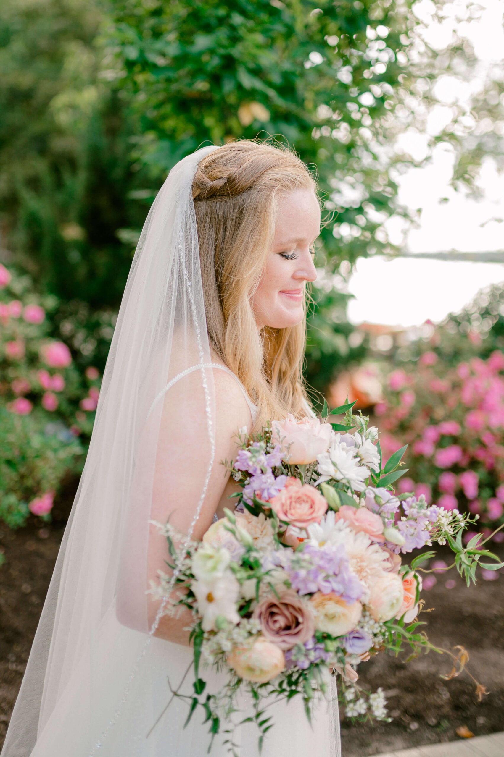 A happy bride walks in a colorful garden holding her large bright bouquet